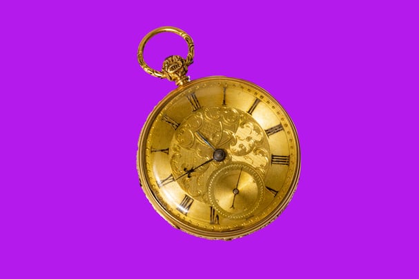 gold pocket watch on pink hero background