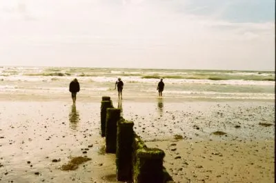 Vintage photograph of three people in the distance walking to the sea on the beach 