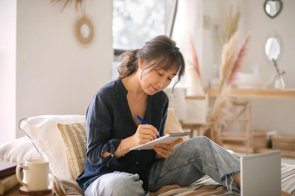 Middle-aged woman smiling down, writing on a pad of paper 