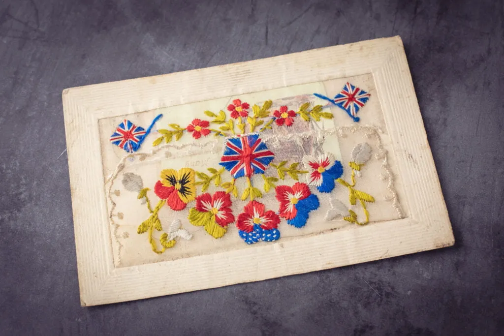 Vintage war postcard with embroidery on lace with British flags and flowers 