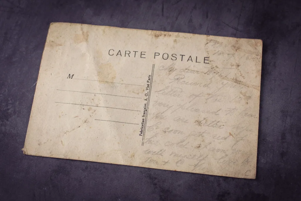 Backside of a vintage war French postcard with very faded illegible cursive script