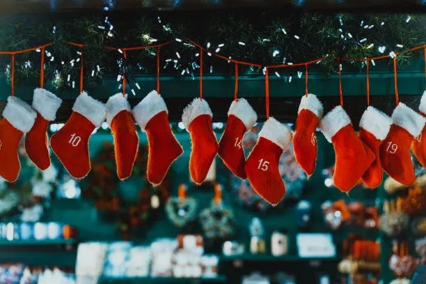 Red fur trimmed Christmas stockings hanging from a garland of lights 