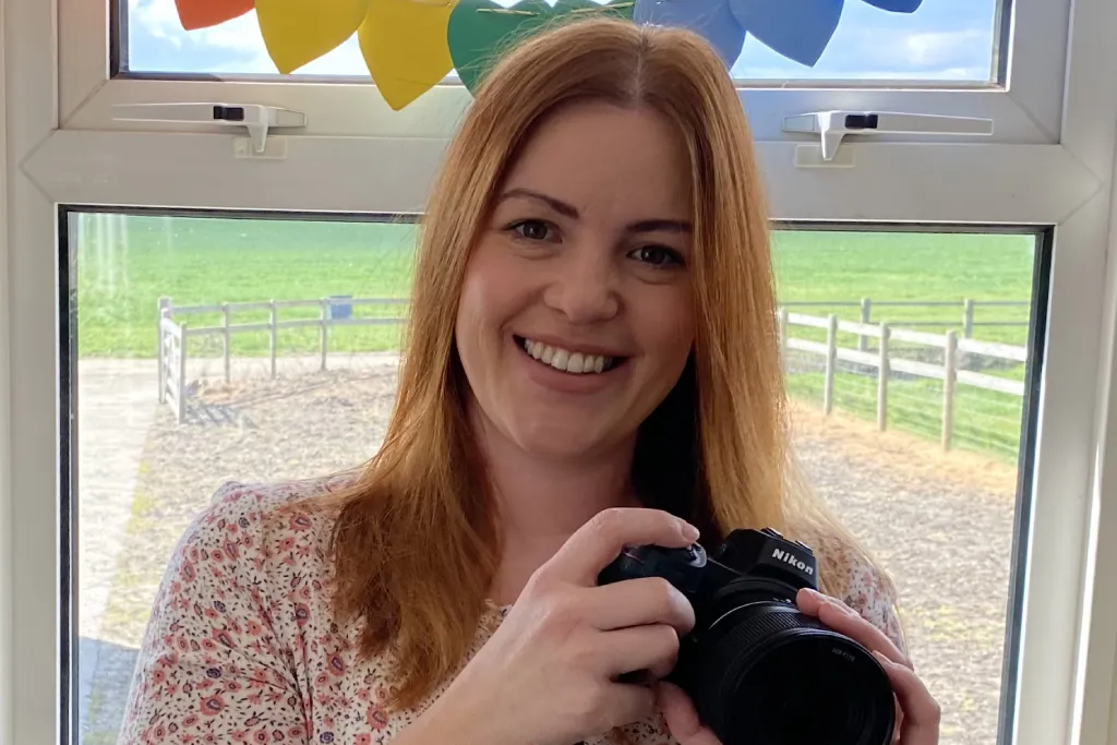 Woman smiling holding an SLR camera