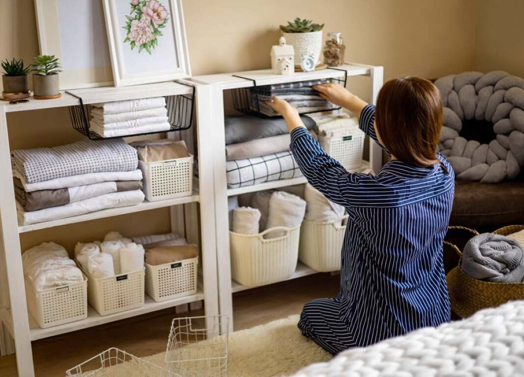 woman folding towels and putting them into a cabinet